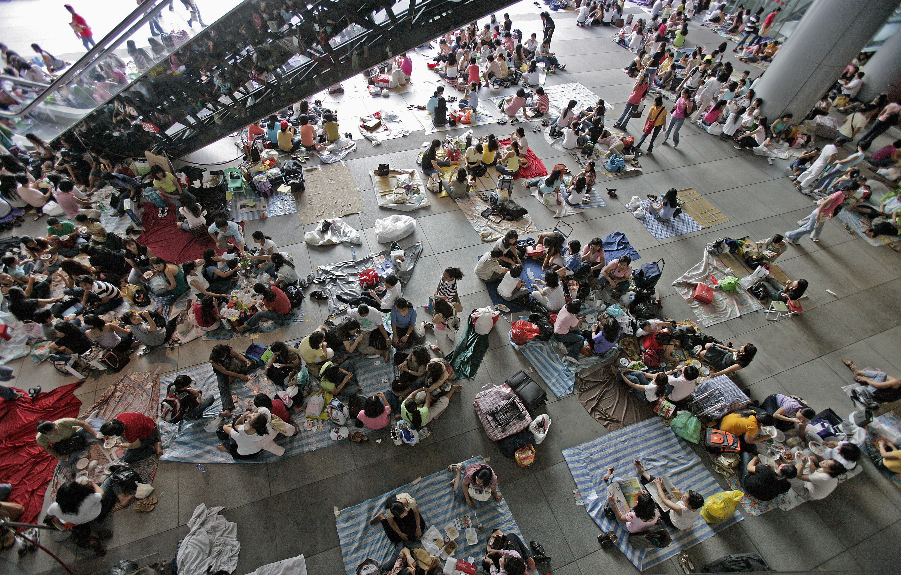 Filipino workers gather at the HSBC building in the central business district of Hong Kong, China, on Sunday, August 13, 2006. Overseas Filipinos sent home more money in June compared with a year before, helping keep remittances on track to meeting the government's 10 percent full-year growth target. Photographer: Paul Hilton/Bloomberg News.