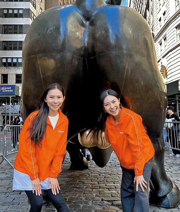Race與Rhonda身穿橙色制服,在紐約地標之一華爾街銅牛(Charging Bull)前影相留念。