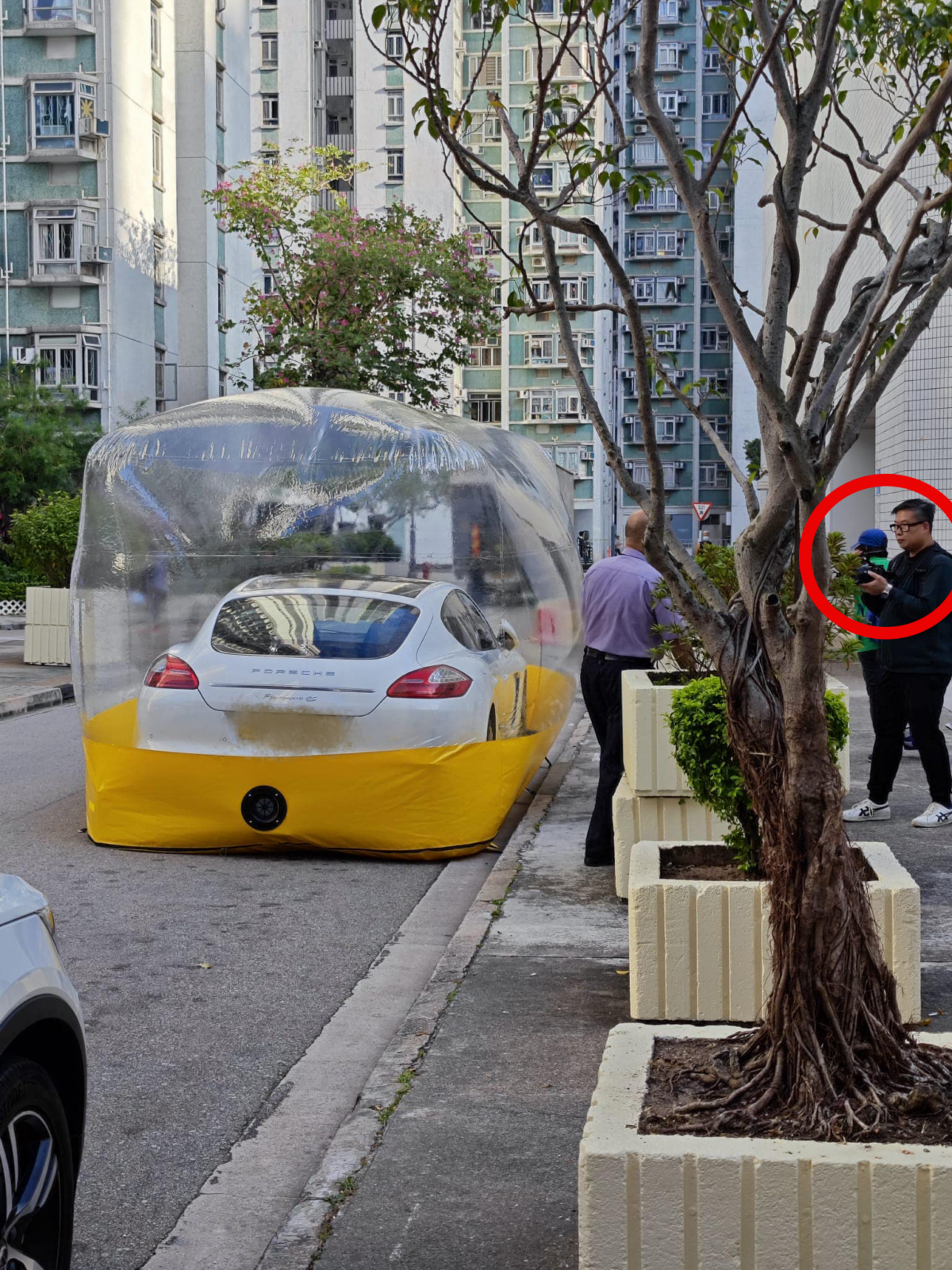 保時捷旁邊站著一名黑衣男子，正拿著專業攝影器材進行拍攝。