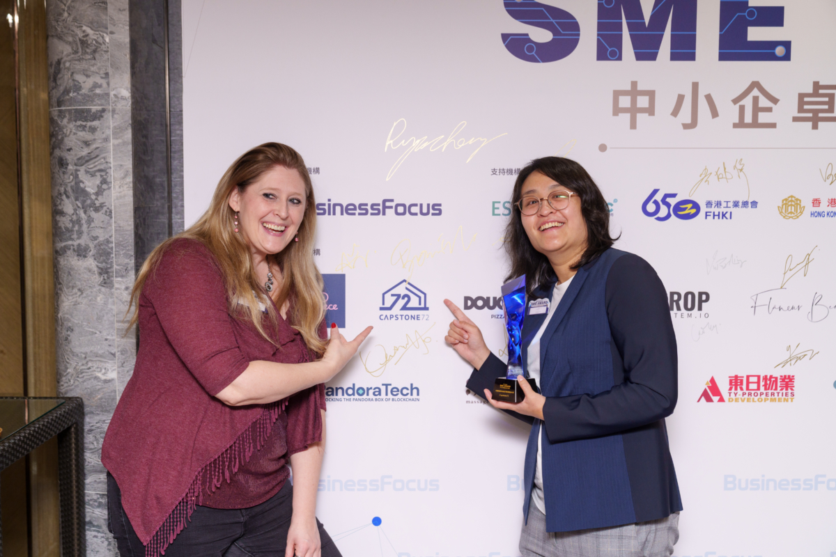 Capstone72 兩位得獎代表於簽名板前合照,Capstone72 CEO Bonnie Wu(右)高舉藍水晶獎座