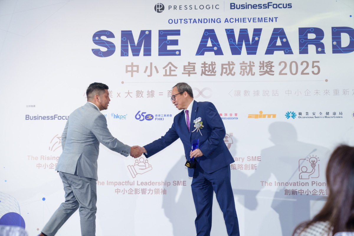 香港工業總會副主席岑健偉先生(右)頒發獎項,在 BusinessFocus 中小企卓越成就獎 2025 舞台握手,手持藍水晶獎座